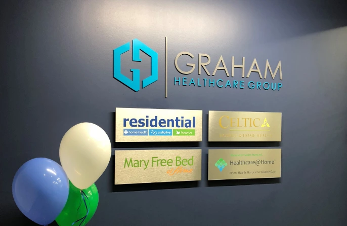 An office lobby wall with logo plaques of Graham Healthcare Group and the companies that comprise it